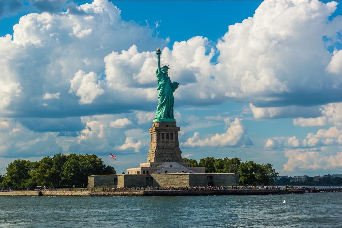 A statue of liberty on the water under cloudy skies.