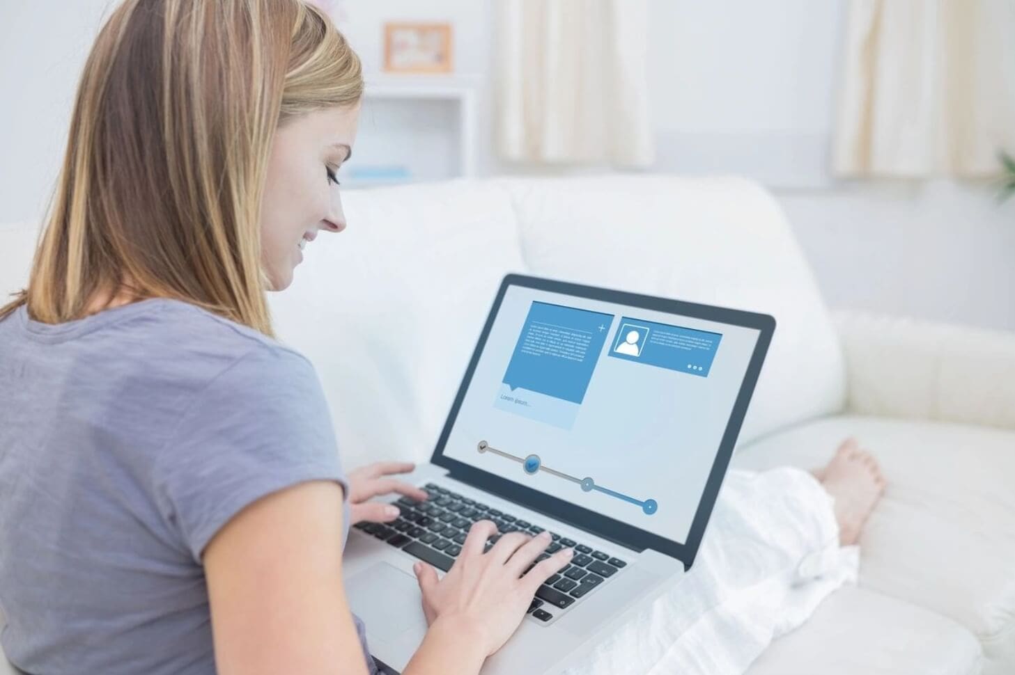 A woman sitting on the couch using her laptop.