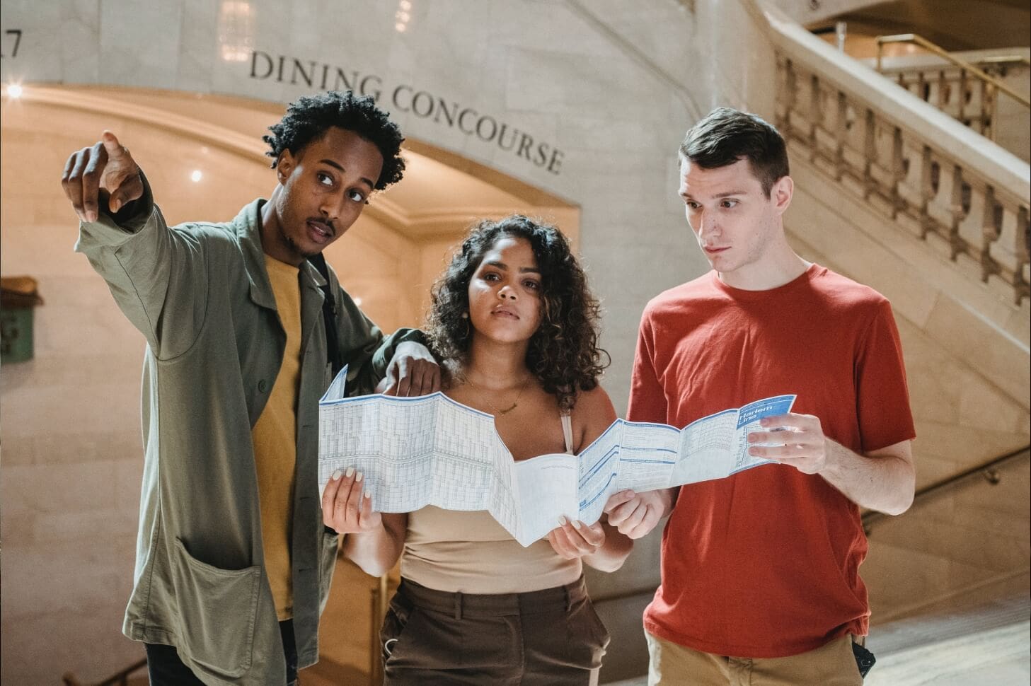 Three people standing in a lobby holding papers.