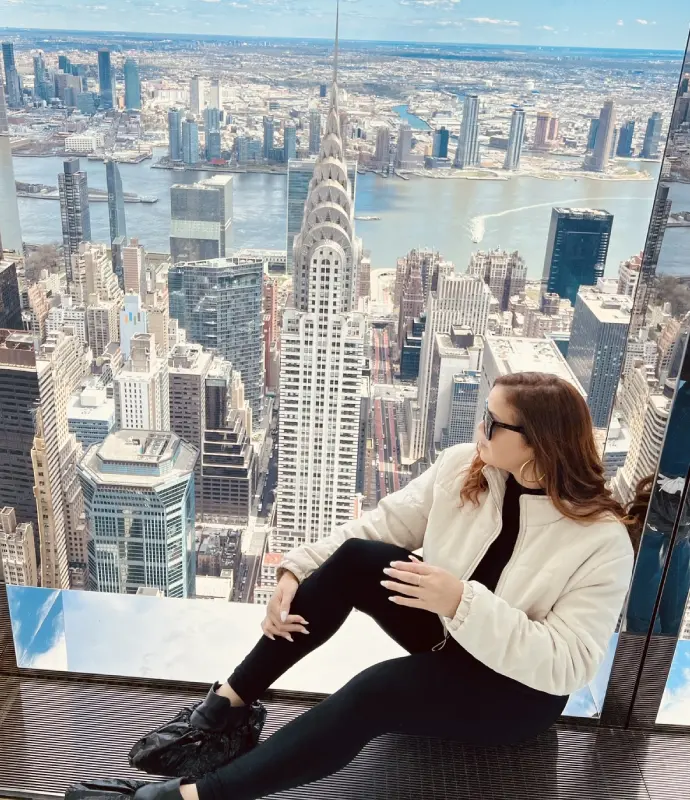 A woman sitting on the ground in front of a large picture.