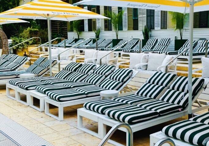 A row of lounge chairs and umbrellas next to the pool.